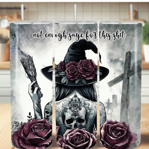 May include: A black and white illustration of a witch with a skull tattoo, holding a smudge stick. The witch is wearing a black hat with a wide brim and has roses in her hair. The background is a watercolor-style image of a graveyard with crosses and clouds. The text "not enough sage for this shit" is written in black at the top of the image.