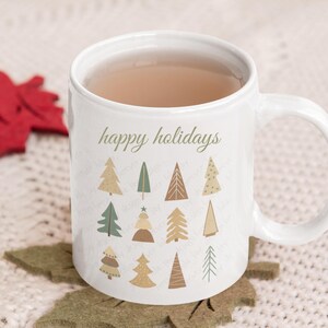 May include: White ceramic mug with a brown handle. The mug has a design of stylized Christmas trees in shades of green, brown, and beige. The text "happy holidays" is printed on the mug.