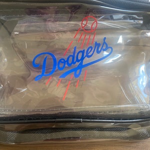 Pu&ograve; includere: Una borsa da viaggio rettangolare trasparente dei Dodgers con cerniera e finiture nere. Il logo dei Dodgers &egrave; in blu con un design a palla da baseball e strisce rosse. La borsa &egrave; in materiale trasparente.
