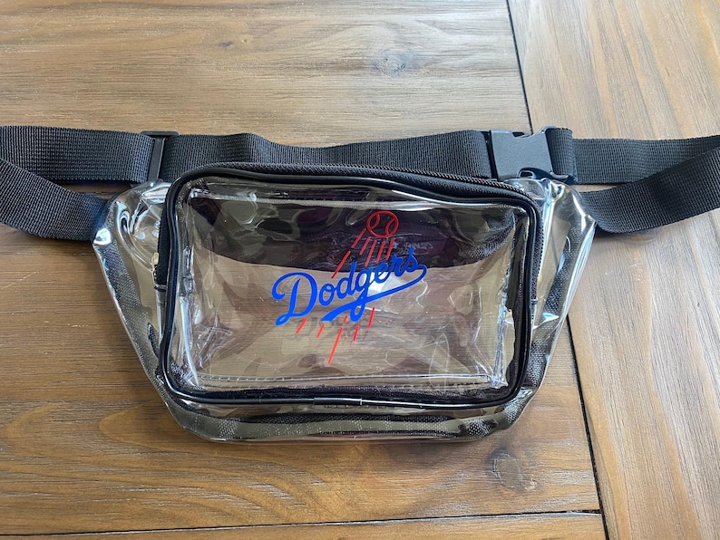 Pu&ograve; includere: Marsupio trasparente con cinturino e fibbia neri regolabili. La parte anteriore del marsupio presenta il logo dei Los Angeles Dodgers in blu, rosso e bianco.