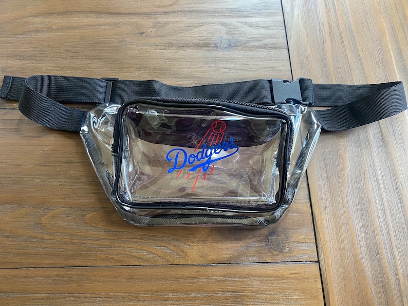 Pu&ograve; includere: Marsupio trasparente con cinturino e fibbia neri regolabili. Il marsupio presenta il logo dei Los Angeles Dodgers in blu e rosso. Il marsupio &egrave; realizzato in materiale trasparente.