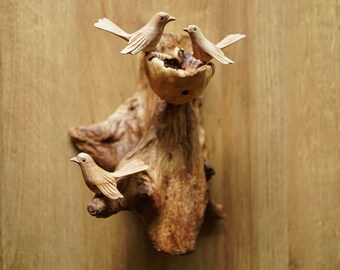 Puede incluir: Decoración de pared de madera con un tronco de árbol tallado con tres pájaros posados en ramas. Los pájaros están tallados en un estilo realista y tienen un acabado de madera natural.