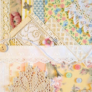 May include: A collage of fabric scraps featuring lace, floral patterns, and decorative elements. The design includes a variety of textures, with a button, a small key, and a miniature Eiffel Tower charm. The color palette is soft, with pastel pinks, yellows, and blues.