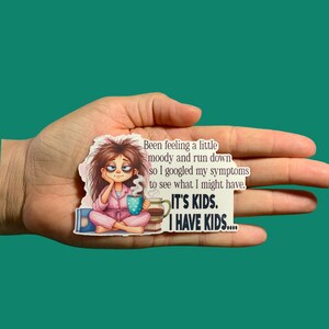 May include: A sticker with a cartoon woman in pajamas holding a mug of coffee. The text reads "Been feeling a little moody and run down so I googled my symptoms to see what I might have. It's kids. I have kids..."