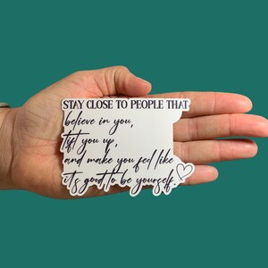 May include: White sticker with black text that reads "STAY CLOSE TO PEOPLE THAT believe in you, lift you up, and make you feel like it's good to be yourself." A small heart is drawn next to the text.