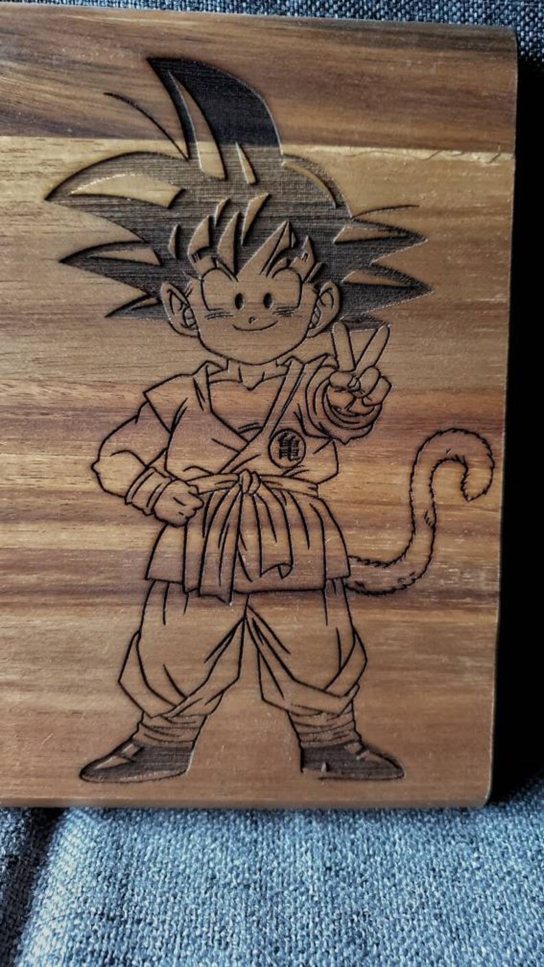 May include: A wooden plaque with a laser-engraved image of a cartoon character with spiky hair, a peace sign, and a tail. The character is wearing a martial arts uniform with a symbol on the chest.