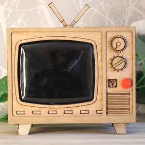 May include: A white ceramic mug with a black handle and the text "But First, Coffee" in a black, bold font. The mug is sitting on a wooden surface. The mug is approximately 4 inches tall.