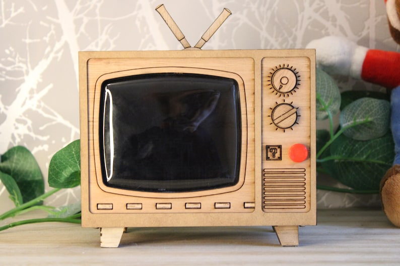 May include: A white ceramic mug with a black handle and the text "But First, Coffee" in a black, bold font. The mug is sitting on a wooden surface. The mug is approximately 4 inches tall.