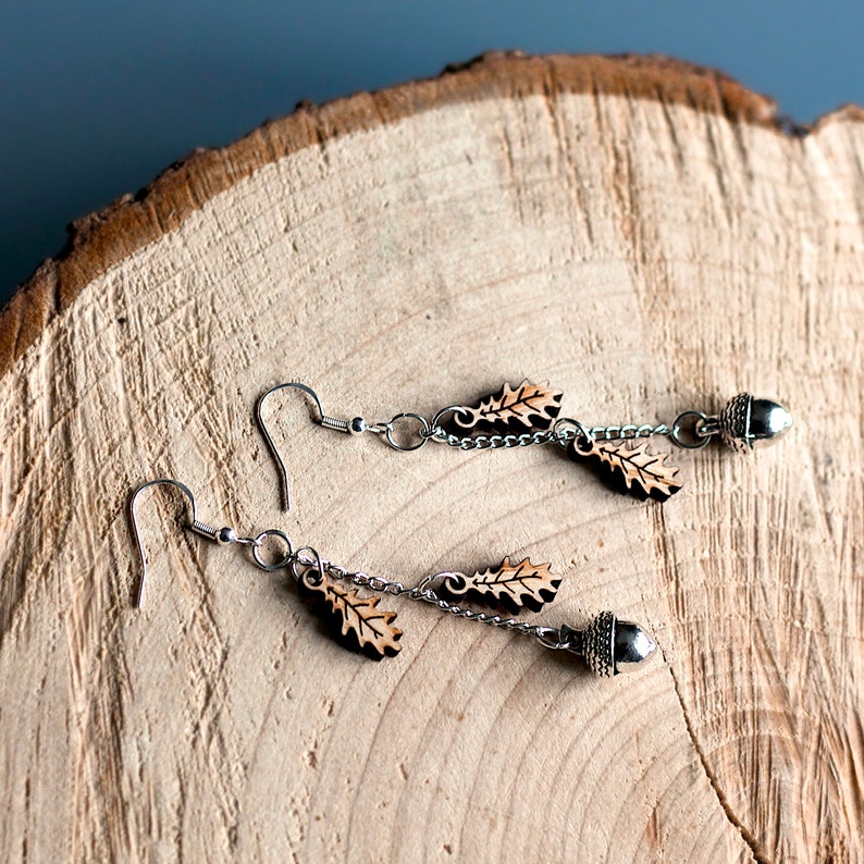 Oak leaf and Acorn earrings displayed on a log slice. The Oak leaf charms are engraved and cut from wood using a laser.