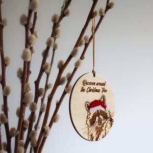 Side view of hanging raccoon ornament. The mix of texture and layers add interest to this handcrafted, original piece designed and made by a small business based in the UK.