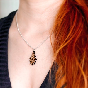 Oak leaf pendant necklace being worn by a woman with long red hair on a silver plated chain.