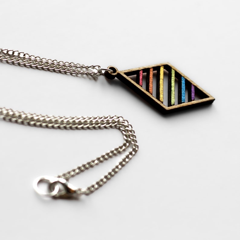 Close up on white background of wooden pendant on a silver plated chain. Pendant is a wooden diamond frame rainbow accents. Chain has a lobster clasp and large end ring for easy attachment.