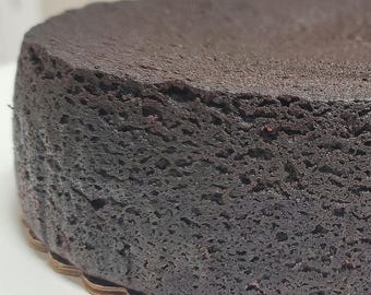 以下が含まれることがあります： チョコレートケーキの層のクローズアップで、ケーキのテクスチャがわかります。ケーキは丸く、表面がわずかに不均一です。