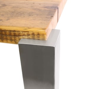 Könnte beinhalten: Nahaufnahme einer Tischplatte aus Holz mit natürlicher Holzmaserung. Die Tischplatte wird von einem silbernen Metallbein getragen.