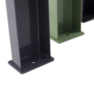 May include: Close-up of the base of three metal legs, one black, one green, and one black. The legs are square and have a flat base with a small hole in the center.