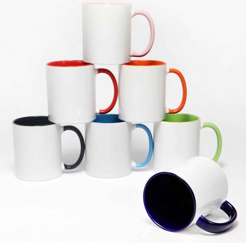 May include: A stack of white ceramic mugs with colored interiors and handles. The mugs have a variety of colors, including pink, red, orange, green, blue, and black. The mugs are stacked in a pyramid shape.