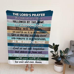 May include: A blue and white throw blanket with the Lord's Prayer printed on it. The text is in a white font and is centred on the blanket. The blanket is made of a soft, comfortable material and is perfect for snuggling up on the sofa.