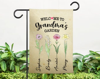 May include: A brown garden flag with the text "Welcome to Grandma's Garden" and four flowers with the names "Sophia", "Brady", "Annabel", and "Maxcy" written below them.