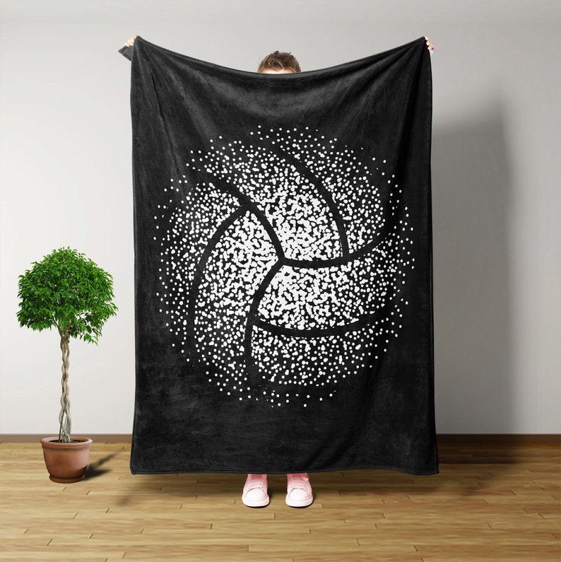 K&ouml;nnte beinhalten: Schwarze Fleece-Decke mit einem wei&szlig;en Volleyball-Design. Der Volleyball besteht aus wei&szlig;en Punkten, die die Form des Balls bilden.