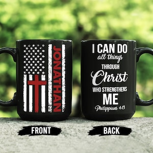 May include: Black ceramic mug with a handle. The front features a distressed American flag design with a red cross and the name "JONATHAN". The back displays the text "I CAN DO all things THROUGH Christ WHO STRENGTHENS ME" and "Philippians 4:13".