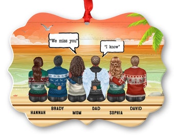 May include: A Christmas ornament featuring a family of seven people standing on a beach with a sunset in the background. The ornament has the text "We miss you" and "I know" on it. The family members are labeled Hannah, Brady, Mom, Dad, Sophia, and David.