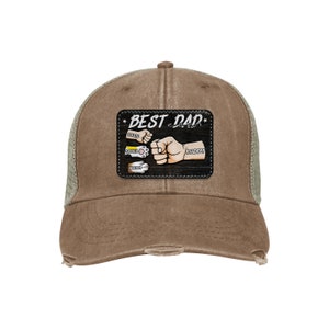 May include: A brown and green distressed trucker hat with a black patch that says "BEST DAD EVER" with a paw print and the words "DAITO", "SUZIE", and "FLUFFY" on it.