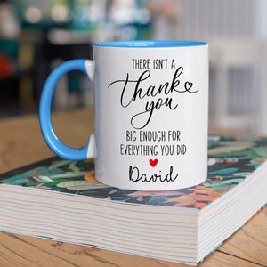 May include: White ceramic mug with a blue interior and handle. The mug features the text "There isn't a Thank you big enough for everything you did" in black script, with a red heart and the name "David" below.