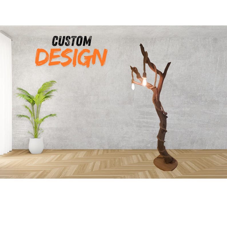 May include: A custom-designed floor lamp made from a natural tree branch with three light bulbs. The lamp is standing on a wooden floor in front of a gray wall. The text "CUSTOM DESIGN" is written in orange letters on the wall.