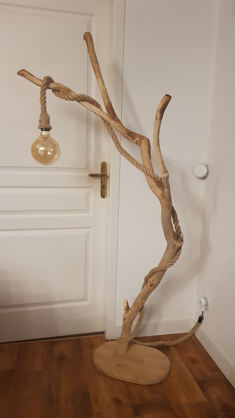May include: A floor lamp made from a natural branch with rope wrapped around it. The lamp has a single light bulb and a wooden base.