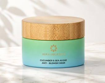 Könnte beinhalten: Ein zylindrischer Tiegel mit einem hellen Holzmaserungsdeckel und einem Farbverlauf, der von Grün oben zu Blau unten übergeht. Der Text Aura Organics Cucumber & Sea Algae Anti-Blemish Mask ist in Gold und Schwarz auf der Vorderseite aufgedruckt.