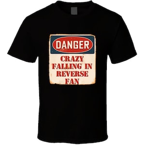 以下が含まれることがあります： 「Danger Crazy Falling in Reverse Fan」と書いてあるビンテージ風の警告標識がついた黒いTシャツ。