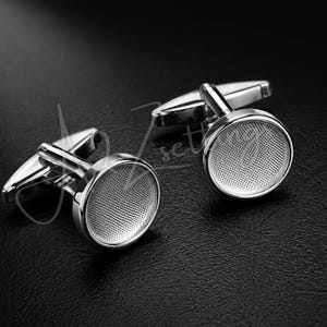 May include: A pair of silver-toned cufflinks featuring a circular face with a fine, textured mesh pattern. Each cufflink has a polished metal rim and a standard toggle closure mechanism on the back, designed for securing shirt cuffs.