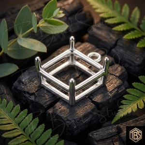 May include: A square silver pendant setting featuring four vertical prongs at each corner to secure a gemstone. The metal frame has a polished finish and includes a small circular jump ring attached to one side for hanging on a chain or cord.