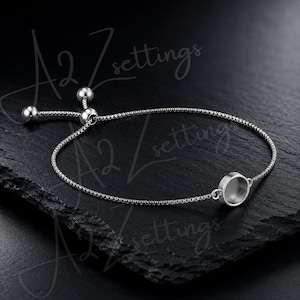 Puede incluir: Una pulsera ajustable plateada con un engaste redondo. La pulsera presenta una fina cadena y dos pequeñas cuentas redondas en el cierre ajustable. El engaste está diseñado para sujetar un pequeño dije o piedra.