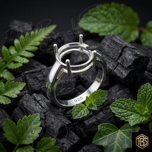 Può includere: Una montatura per anello in argento lucido con una testa a quattro griffe progettata per sostenere una pietra preziosa. L'interno della fascia è chiaramente stampigliato con il numero 925, che indica la purezza del metallo. L'anello ha una superficie liscia.