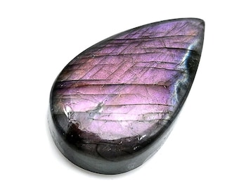 May include: A polished, teardrop-shaped gemstone with a vibrant display of purple and pink hues. The stone's surface features a textured, linear pattern, and the edges are a deep, dark gray. The gemstone is set against a bright white background.