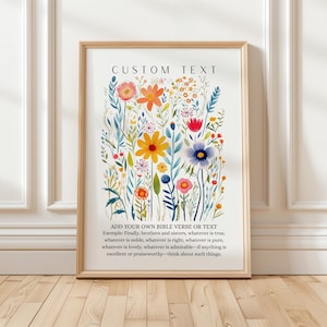 May include: A framed floral art print with a watercolor design. The print features colorful flowers in shades of orange, yellow, blue, and pink, with the text "CUSTOM TEXT" at the top. The bottom text reads "ADD YOUR OWN BIBLE VERSE OR TEXT".