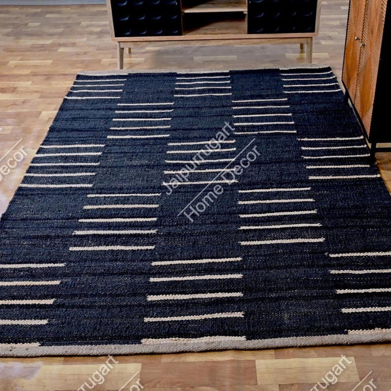 May include: A rectangular area rug featuring a dark navy blue base with a repeating pattern of horizontal white stripes. The rug has a textured, woven appearance and is laid flat on a light-colored wooden floor, showcasing a clean, geometric design.