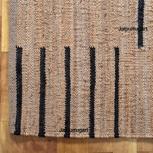 May include: A natural fiber rug with black stripes. The rug is made of jute and has a natural, earthy look. The rug is perfect for adding a touch of rustic charm to any room.