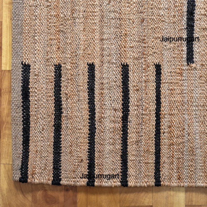 May include: A natural fiber rug with black stripes. The rug is made of jute and has a natural, earthy look. The rug is perfect for adding a touch of rustic charm to any room.