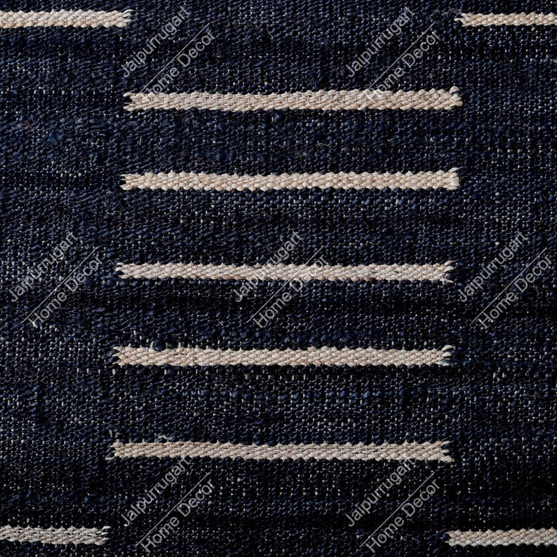 May include: A dark navy blue textile fabric featuring a repeating pattern of horizontal, light beige, textured stripes. The weave of the fabric is visible, showing a coarse, dense, and uniform construction throughout the entire surface area.