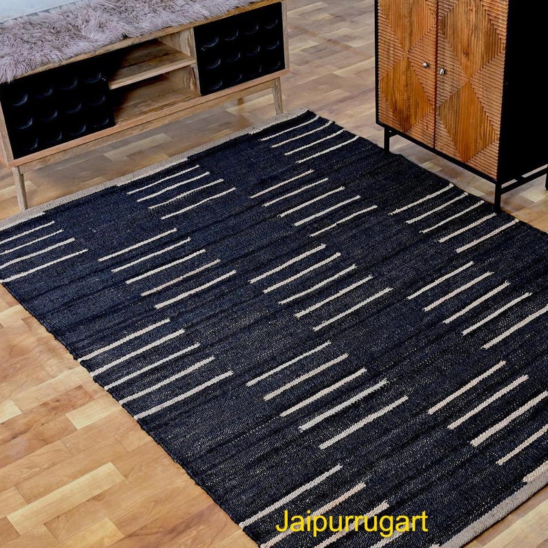 May include: A rectangular area rug featuring a dark black base color with a repeating pattern of short, horizontal, off-white dashed lines arranged in staggered vertical columns across the entire surface of the woven floor covering.
