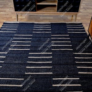 May include: A rectangular area rug featuring a deep navy blue base with a repeating geometric pattern of horizontal white stripes. The rug has a textured, woven appearance with a consistent grid-like layout across the entire surface area.