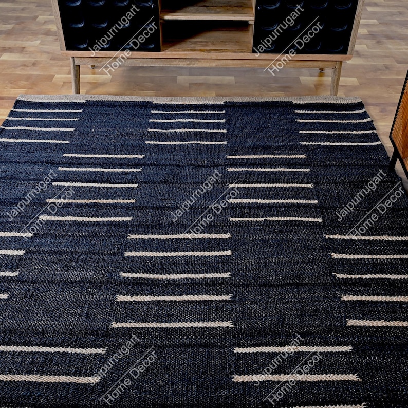 May include: A rectangular area rug featuring a deep navy blue base with a repeating geometric pattern of horizontal white stripes. The rug has a textured, woven appearance with a consistent grid-like layout across the entire surface area.