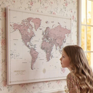 May include: A framed world map in pink tones hangs on a floral wallpapered wall. A young person gazes at the map. A wooden chest with a decorative box sits below the map. A bookshelf and window are also visible.