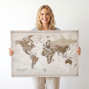 Peut inclure: Une grande carte du monde rectangulaire imprimée sur un fond beige clair, avec des continents représentés en différentes nuances de brun. La carte comprend une bordure décorative, une rose des vents et le texte EMILY & OLIVER en bas à gauche.