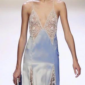 Front-view close-up of a model on the runway, capturing the delicate texture of the hand-stitched lace and the elegant sheen of the premium silk-blend fabric.