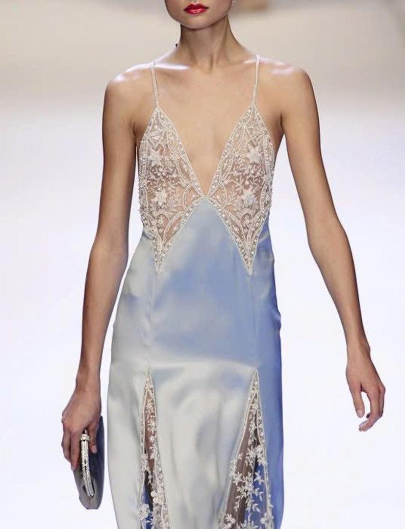 Front-view close-up of a model on the runway, capturing the delicate texture of the hand-stitched lace and the elegant sheen of the premium silk-blend fabric.