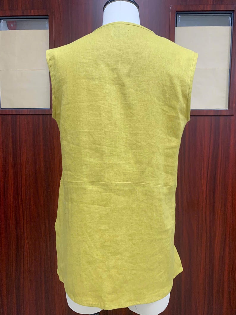 Back view of the chartreuse linen tunic on the dress mannequin, showcasing the simple high crew neckline at the back and the straight, relaxed-fit hemline.