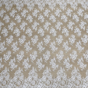 Beige lace wedding gown fabric swatch with white floral lace and scalloped edges